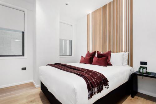 Un dormitorio con una gran cama blanca con almohadas rojas. en Victoria Street Apartments by Urban Rest, en Auckland
