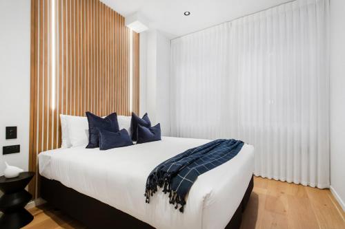 a bedroom with a large bed with blue pillows at Victoria Street Apartments by Urban Rest in Auckland