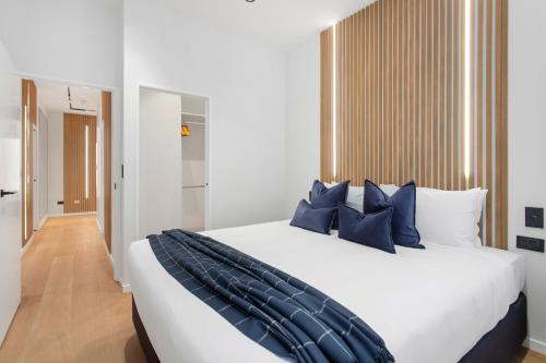 a bedroom with a large white bed with blue pillows at Victoria Street Apartments by Urban Rest in Auckland