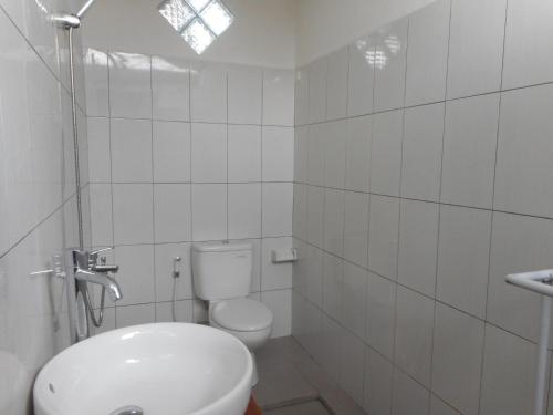 a white bathroom with a toilet and a sink at Lila Stana - Sidemen Homestay in Sidemen