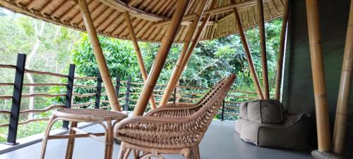 a porch with two chairs and a table and a stool at La Quoriena Botanical Villa & Cafe' in Labuan Bajo