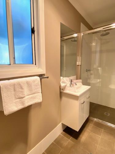 a bathroom with a sink and a shower and a mirror at Huskisson Beach Escape in Huskisson