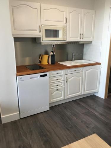 une cuisine avec des armoires blanches et un réfrigérateur blanc dans l'établissement Studio Héliopolis vue mer village naturiste, au Cap d'Agde