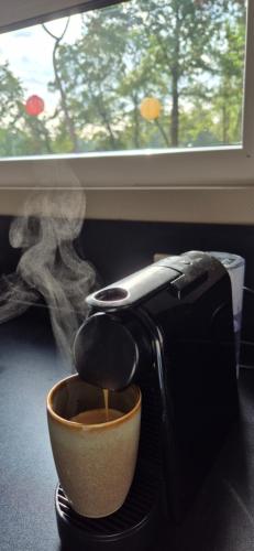 a coffee maker sitting next to a cup of coffee at Hellendoornse boshuisje Tranquilo in Haarle
