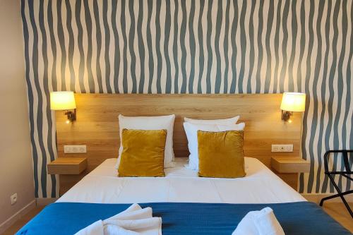 a bedroom with a bed with two yellow pillows at Aparthotel AMMI Nice Massena - ex Ajoupa in Nice