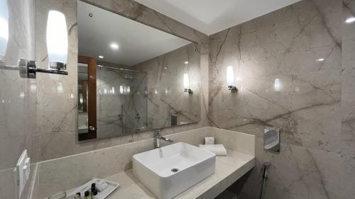 a white bathroom with a sink and a mirror at Katriya Hotel and Tower in Hyderabad