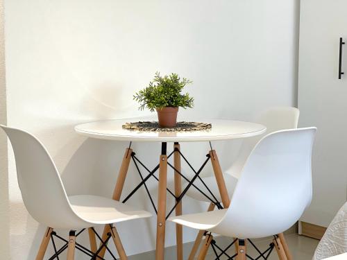 a table with white chairs and a potted plant on it at LAGUNA Apartments in Vranje