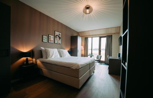 a bedroom with a large bed and a large window at Boutique Hotel het Witte Veen in Witteveen