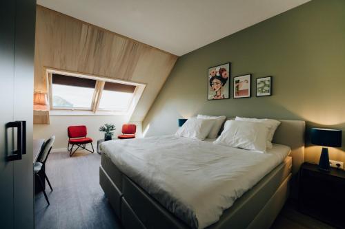 a bedroom with a large bed and two red chairs at Boutique Hotel het Witte Veen in Witteveen