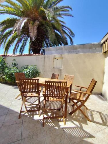 une table en bois et quatre chaises et un palmier dans l'établissement Maison 8 couchages Arcachon, à Arcachon