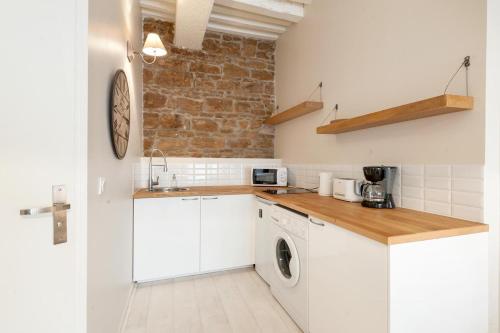 une cuisine avec des armoires blanches et une laveuse et une sécheuse dans l'établissement GuestReady - Charmant studio proche du métro, à Lyon