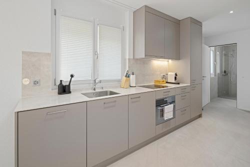 a white kitchen with white cabinets and a sink at STAYY Flagship Limmattal - contactless check-in in Schlieren