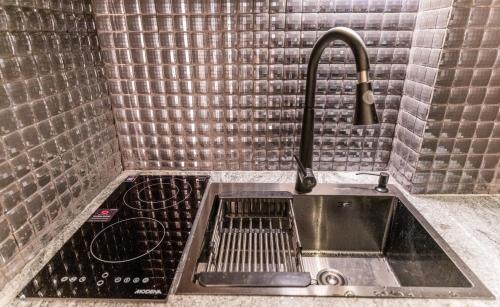 a kitchen sink with a faucet in a bathroom at Pentacity Hotel Balikpapan in Balikpapan