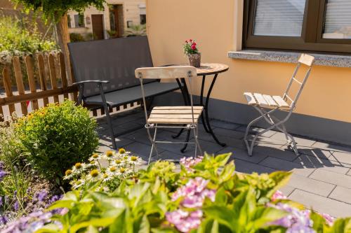 a patio with two chairs and a table and some flowers at Haus Jakob in Longkamp