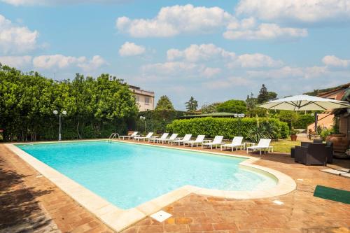 a swimming pool with chairs and an umbrella at Villa delle Rose by VacaVilla in Magione