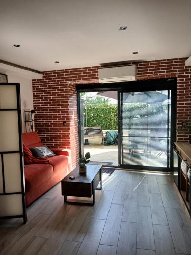 - un salon avec un canapé rouge et un mur en briques dans l'établissement Disneyland Paris Studio avec Terrasse, à Chalifert