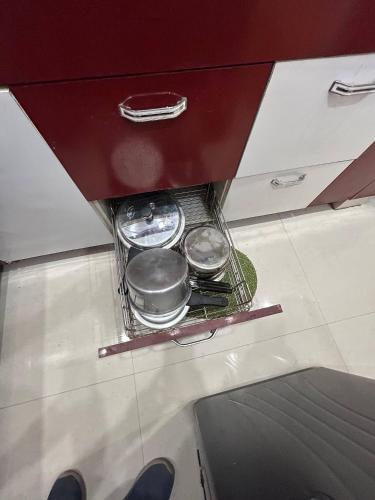 a person standing under a kitchen counter with three pans at Entire 3bhk Luxury Flat in Zirakpur-Panchkula-Chandigarh-Mohali, Punjab, India in Zirakpur
