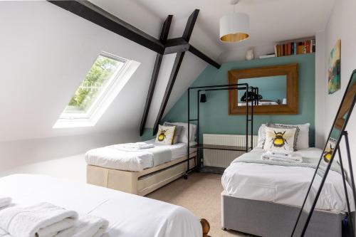 a attic bedroom with two beds and a mirror at The Coach House in Lea