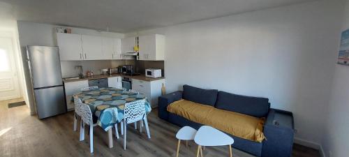 un salon avec un canapé bleu et une table dans l'établissement Les Baleinières Les Sables d'Olonne La Chaume, à Les Sables-dʼOlonne