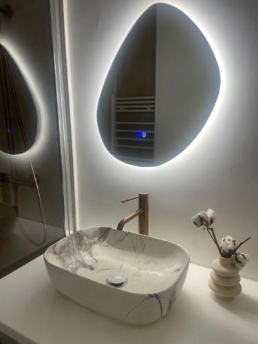 La salle de bains est pourvue d'un lavabo en marbre et d'un miroir. dans l'établissement Charmant studio perché sur les toits, avec ascenseur, 16 ème quartier calme securise- Proche quai Seine, à Paris