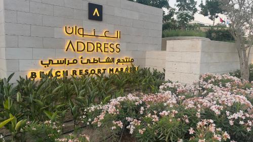 a sign for the address of a building with flowers at Marassi, Luxury Suite in Address Beach resort! service apartment in El Alamein
