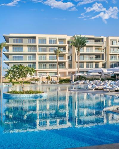 a hotel with a swimming pool in front of a building at Marassi, Luxury Suite in Address Beach resort! service apartment in El Alamein