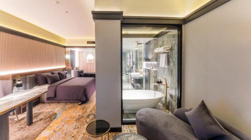 a bedroom with a bed and a bath tub and a sink at Pentacity Hotel Balikpapan in Balikpapan