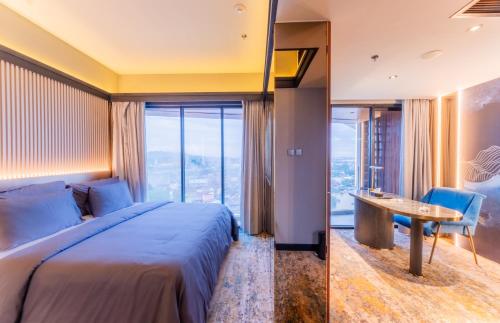 a bedroom with a bed and a desk and a window at Pentacity Hotel Balikpapan in Balikpapan