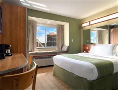 a bedroom with a bed and a desk and a window at Microtel Inn & Suites by Wyndham Saraland in Saraland