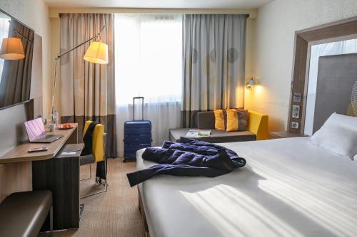 a hotel room with two beds and a desk at Novotel Le Mans in Le Mans
