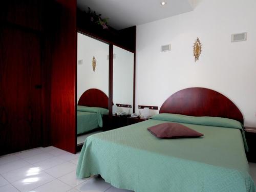 a bedroom with a green bed and a mirror at Hotel Carosello in Pontecagnano