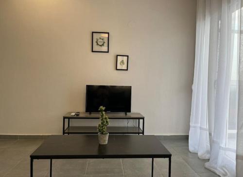 a living room with a table and a tv at HomeBak Hospitality in Xanthi