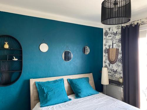 une chambre avec des murs bleus et un lit avec des oreillers bleus dans l'établissement Appartement au bord de la mer, à Canet
