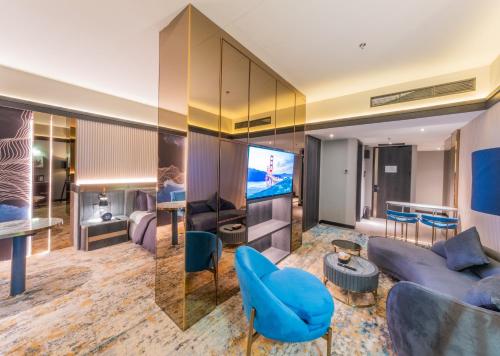 a living room with a blue couch and a tv at Pentacity Hotel Balikpapan in Balikpapan