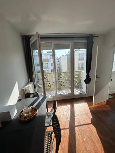 une pièce avec une table et des chaises et une grande fenêtre dans l'établissement Appartement meublé très bien situé, à Boulogne-Billancourt