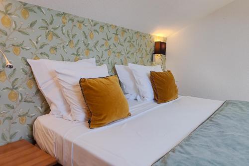 a bedroom with a bed with white sheets and pillows at Aparthotel AMMI Nice Massena - ex Ajoupa in Nice