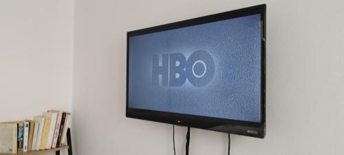 Elle comprend une télévision à écran plat installée sur un mur. dans l'établissement Cosy studio centre Versailles, à Versailles