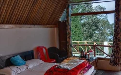 a bedroom with a bed and a large window at Amar Bari Happy Valley Cottages by StayApart in Mangpu