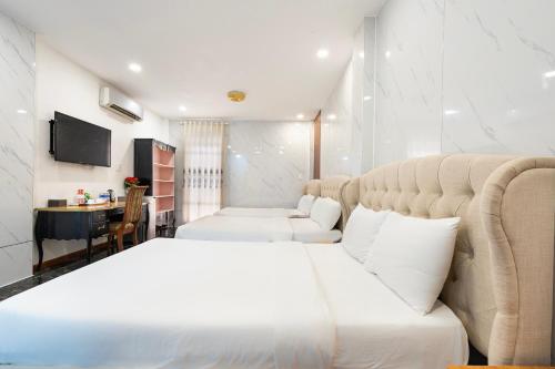 a bedroom with a large white bed and a desk at Lam Kinh Hotel in Ho Chi Minh City