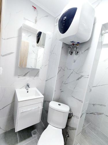 a white bathroom with a toilet and a sink at SOLI Apartment in Neoi Epivates