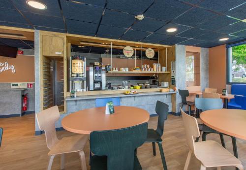 un restaurant avec deux tables et des chaises ainsi qu'une cuisine dans l'établissement B&B HOTEL Châteauroux A20 L'Occitane, à Déols