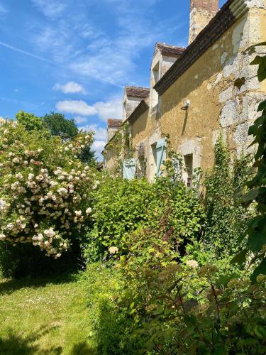 un vieux bâtiment en pierre avec des fleurs devant lui dans l'établissement La Breteche du Perche, à Saint-Germain-de-la-Coudre