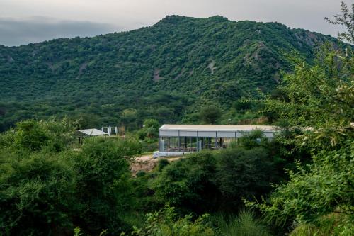 a building in front of a mountain with trees at Teela- The Glamping Resort, Jaipur in Udāsar