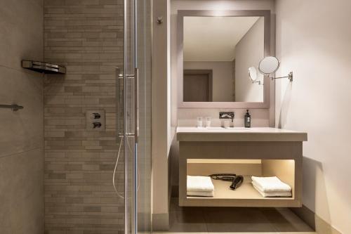 a bathroom with a shower and a sink and a mirror at Ramada Plaza by Wyndham Batumi & Casino in Batumi