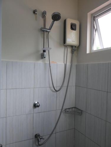 a shower with a shower head in a bathroom at TLT Guesthouses - Dauin in Dauin