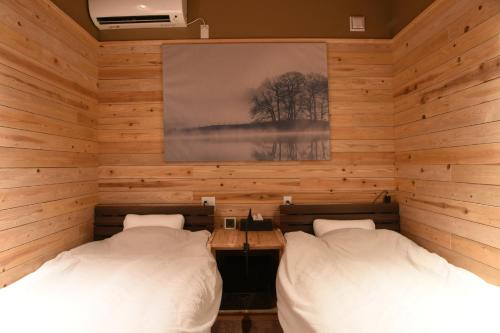 two beds in a room with wooden walls at アングラーズベース下北山 in Kami-ikehara