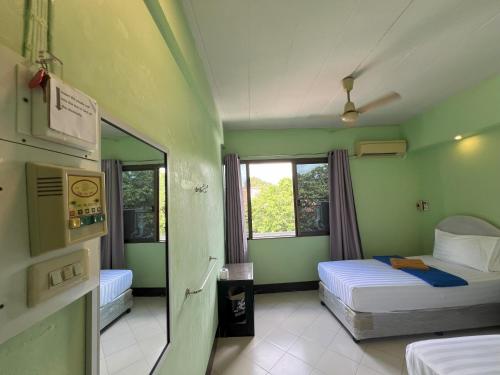 a green room with two beds and a window at Bella Bella House in Bangkok