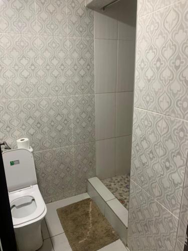 a bathroom with a toilet and a tile wall at Angel Guest House in Johannesburg