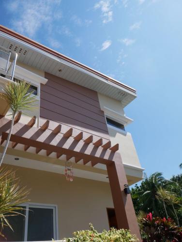 a house with a pergola on the side of it at TLT Guesthouses - Dauin in Dauin