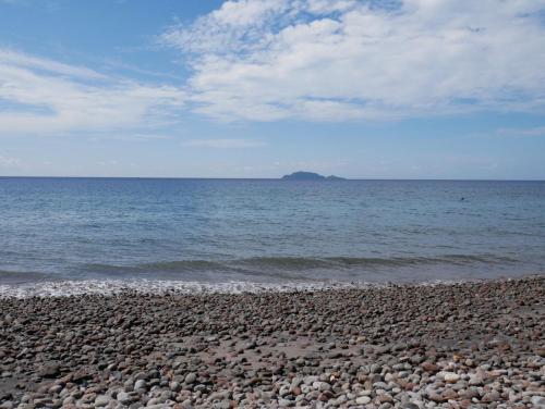 a rocky beach with an island in the ocean at TLT Guesthouses - Dauin in Dauin